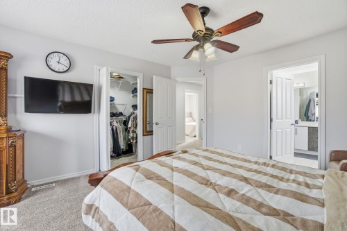 Bedroom featuring a spacious closet, light colored carpet, a textured ceiling, ceiling fan, and ensuite bath - 1532 37C Avenue, Edmonton, AB - Indoor Photo Showing Bedroom