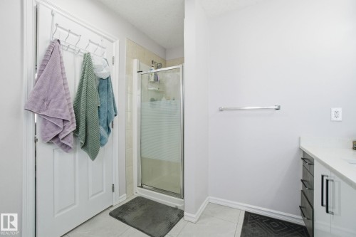 Bathroom featuring a shower stall, vanity, a textured ceiling, and light tile patterned floors - 1532 37C Avenue, Edmonton, AB - Indoor