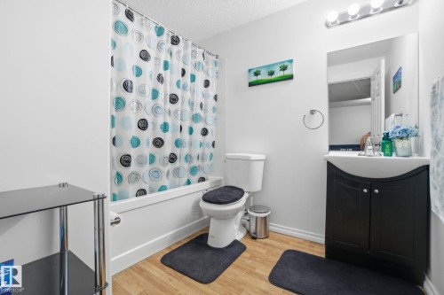 Bathroom with vanity, light wood-style floors, shower / bath combo with shower curtain, and a textured ceiling - 1532 37C Avenue, Edmonton, AB - Indoor Photo Showing Bathroom