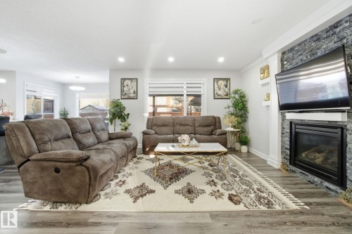 Living room featuring wood finished floors, a stone fireplace, and recessed lighting - 1532 37C Avenue, Edmonton, AB - Indoor Photo Showing Living Room With Fireplace