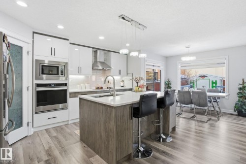 Kitchen with white cabinets, modern cabinets, tasteful backsplash, appliances with stainless steel finishes, and light wood-type flooring - 1532 37C Avenue, Edmonton, AB - Indoor Photo Showing Kitchen With Upgraded Kitchen