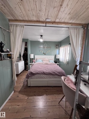 Bedroom featuring hardwood / wood-style flooring, wood ceiling, and wooden walls - #44 9501 104 Ave, Westlock, AB - Indoor Photo Showing Bedroom