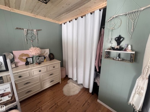 Bedroom with wood walls, wood ceiling, and dark wood-style flooring - #44 9501 104 Ave, Westlock, AB - Indoor Photo Showing Other Room
