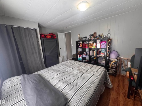 Bedroom with dark wood finished floors and wood walls - #44 9501 104 Ave, Westlock, AB - Indoor Photo Showing Bedroom