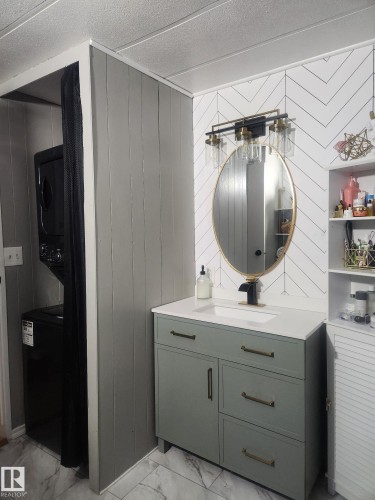 Bathroom with light marble finish flooring, stacked washer and dryer, vanity, and a textured ceiling - #44 9501 104 Ave, Westlock, AB - Indoor Photo Showing Other Room