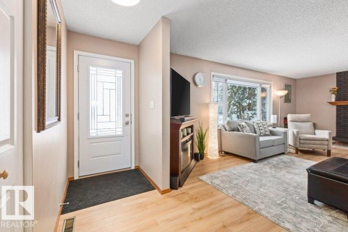 Foyer with a textured ceiling, light wood finished floors, and a fireplace - 1 Larkspur Crescent, St. Albert, AB - Indoor Photo Showing Living Room With Fireplace