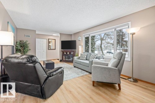 Living area featuring a textured ceiling, light wood-style floors, and a glass covered fireplace - 1 Larkspur Crescent, St. Albert, AB - Indoor Photo Showing Living Room