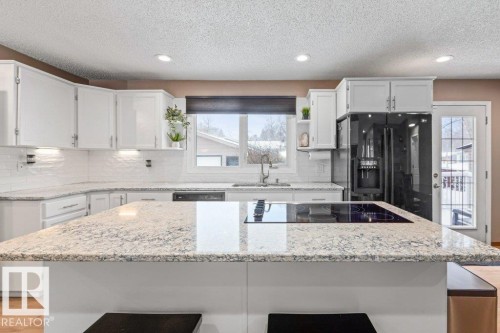 Kitchen with a breakfast bar, white cabinets, a kitchen island, recessed lighting, and a textured ceiling - 1 Larkspur Crescent, St. Albert, AB - Indoor Photo Showing Kitchen With Upgraded Kitchen