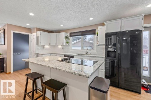 Kitchen with black appliances, a kitchen breakfast bar, a kitchen island, light wood finished floors, and recessed lighting - 1 Larkspur Crescent, St. Albert, AB - Indoor Photo Showing Kitchen With Upgraded Kitchen