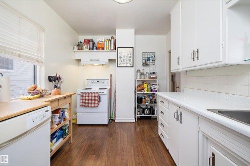Kitchen with white appliances, light countertops, white cabinets, dark wood-type flooring, and backsplash - 11242 72 Avenue, Edmonton, AB - Indoor Photo Showing Kitchen