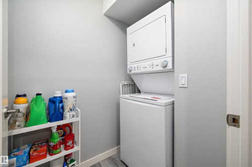 Laundry room with stacked washer / dryer and light wood finished floors - 11242 72 Avenue, Edmonton, AB - Indoor Photo Showing Laundry Room