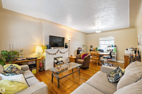 Living room with wood finished floors, a desk, and a textured ceiling - 11242 72 Avenue, Edmonton, AB - Indoor Photo Showing Living Room