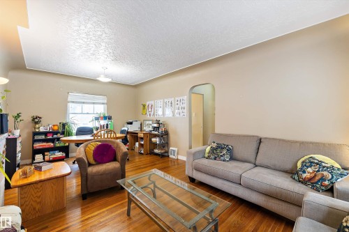Living area featuring arched walkways, a textured ceiling, and hardwood / wood-style flooring - 11242 72 Avenue, Edmonton, AB - Indoor Photo Showing Living Room