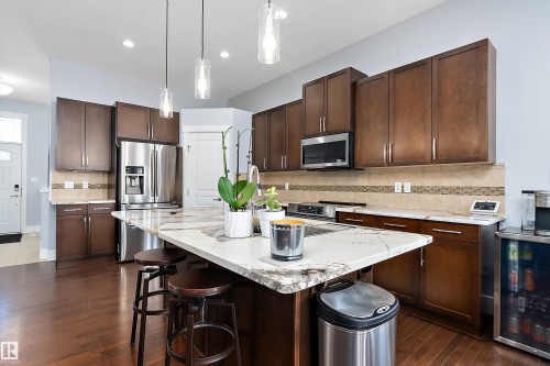 Kitchen with dark brown cabinetry, backsplash, decorative light fixtures, and a kitchen island - 1409 Westerra Bay, Stony Plain, AB - Indoor Photo Showing Kitchen With Upgraded Kitchen