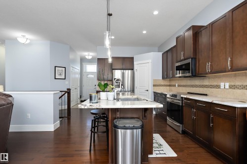 Kitchen with appliances with stainless steel finishes, a kitchen breakfast bar, dark brown cabinetry, hanging light fixtures, and a kitchen island with sink - 1409 Westerra Bay, Stony Plain, AB - Indoor Photo Showing Kitchen With Upgraded Kitchen