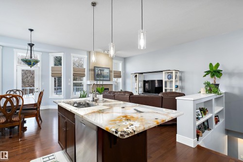 Kitchen featuring dark brown cabinetry, light stone countertops, dishwasher, and dark wood-style floors - 1409 Westerra Bay, Stony Plain, AB - Indoor