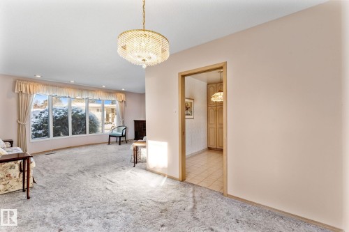 Unfurnished living room with carpet flooring, a fireplace, and suspended lighting - 3519 111B Street, Edmonton, AB - Indoor Photo Showing Other Room