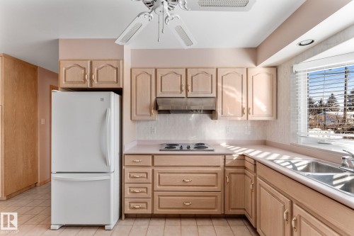 Kitchen with freestanding refrigerator, a ceiling fan, decorative backsplash, and light countertops - 3519 111B Street, Edmonton, AB - Indoor Photo Showing Kitchen With Double Sink