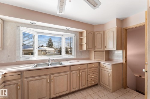 Kitchen with light wood finish cabinets, light countertops, ceiling fan, open shelves, and tasteful backsplash - 3519 111B Street, Edmonton, AB - Indoor Photo Showing Kitchen With Double Sink
