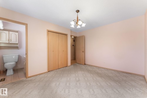 Unfurnished bedroom featuring light carpet, suspended lighting, a closet, and ensuite bath - 3519 111B Street, Edmonton, AB - Indoor