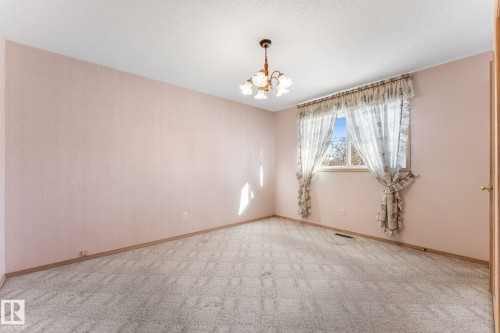 Carpeted spare room featuring a chandelier and a textured ceiling - 3519 111B Street, Edmonton, AB - Indoor Photo Showing Other Room