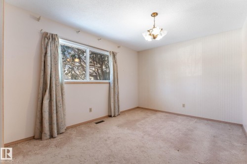 Unfurnished room featuring light colored carpet, a textured ceiling, hanging lights, and wallpapered walls - 3519 111B Street, Edmonton, AB - Indoor Photo Showing Other Room