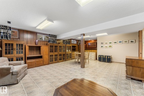 Living room with a textured ceiling, wood walls, and light tile patterned floors - 3519 111B Street, Edmonton, AB - Indoor