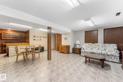 Living area featuring a textured ceiling, wooden walls, and light tile patterned floors - 3519 111B Street, Edmonton, AB - Indoor