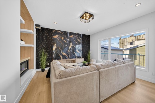 Living room featuring an accent wall, light wood finished floors, recessed lighting, wallpapered walls, and a glass covered fireplace - 9907 68 Street, Edmonton, AB - Indoor