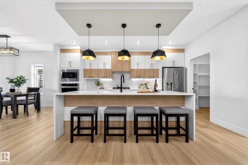 Kitchen featuring hanging light fixtures, a spacious island, and light stone countertops - 9907 68 Street, Edmonton, AB - Indoor