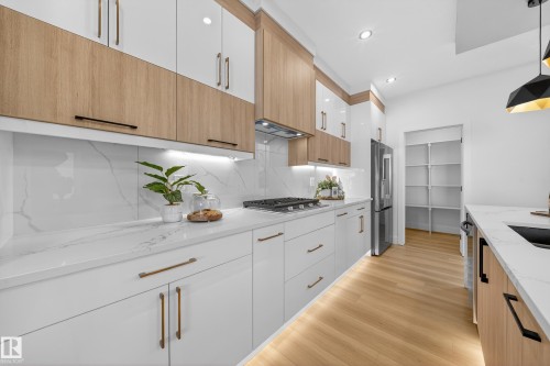 Kitchen with two tone cabinets, light wood finished floors, light stone counters, backsplash, and modern cabinets - 9907 68 Street, Edmonton, AB - Indoor Photo Showing Kitchen With Upgraded Kitchen