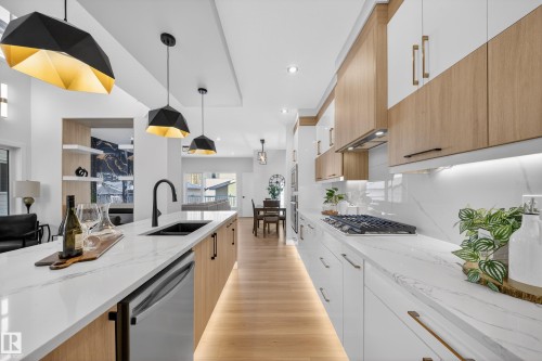 Two tone kitchen with dual tone cabinets, light stone countertops, decorative light fixtures, stainless steel appliances, and modern cabinets - 9907 68 Street, Edmonton, AB - Indoor Photo Showing Kitchen With Double Sink With Upgraded Kitchen