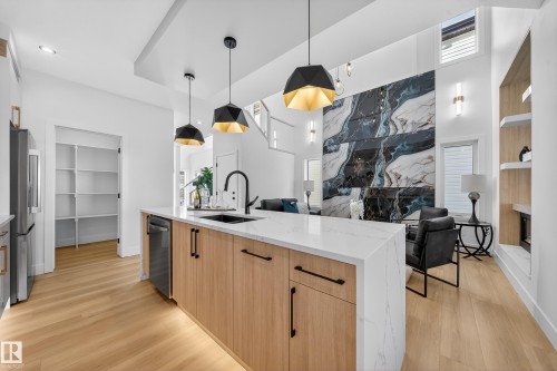 Kitchen with built in features, hanging light fixtures, light wood finish cabinetry, and light stone counters - 9907 68 Street, Edmonton, AB - Indoor Photo Showing Kitchen With Upgraded Kitchen
