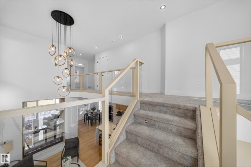 Stairs with wood finished floors and suspended lighting - 9907 68 Street, Edmonton, AB - Indoor Photo Showing Other Room