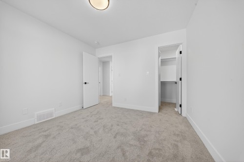 Unfurnished bedroom featuring a spacious closet and light colored carpet - 9907 68 Street, Edmonton, AB - Indoor Photo Showing Other Room