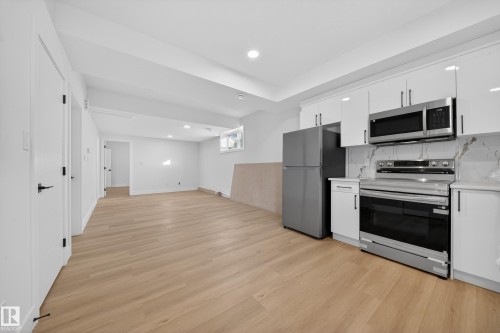 Kitchen with stainless steel appliances, white cabinetry, light wood-style floors, recessed lighting, and open floor plan - 9907 68 Street, Edmonton, AB - Indoor Photo Showing Kitchen