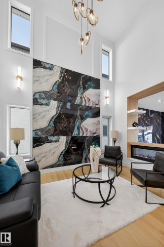 Living room with a premium fireplace, wood finished floors, a high ceiling, and hanging lights - 9907 68 Street, Edmonton, AB - Indoor