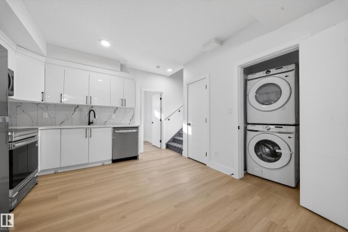 Laundry area with stacked washer and clothes dryer and light wood-type flooring - 9907 68 Street, Edmonton, AB - Indoor Photo Showing Laundry Room
