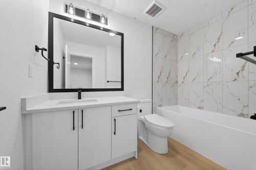 Bathroom with vanity, light wood finished floors, and shower / washtub combination - 9907 68 Street, Edmonton, AB - Indoor Photo Showing Bathroom