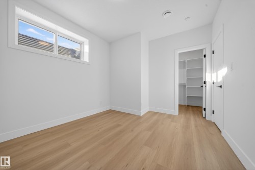 Unfurnished bedroom with a spacious closet and light wood-style flooring - 9907 68 Street, Edmonton, AB - Indoor Photo Showing Other Room