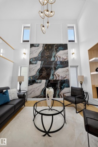 Living room featuring a high ceiling, a chandelier, healthy amount of natural light, and wood finished floors - 9907 68 Street, Edmonton, AB - Indoor
