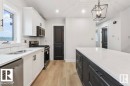 Kitchen with stainless steel appliances, light stone countertops, white cabinets, hanging light fixtures, and recessed lighting - 1432 Wildrye Crescent, Cold Lake, AB  - Indoor Photo Showing Kitchen With Double Sink 