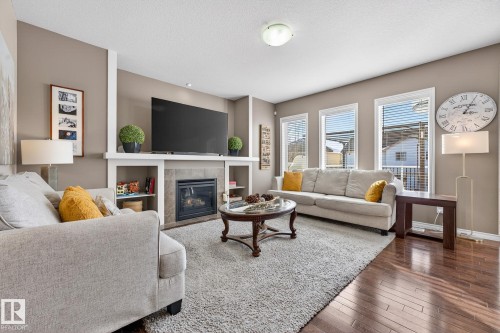 Living room featuring a tile fireplace, dark wood-style flooring, and a textured ceiling - 1734 63A Street, Edmonton, AB - Indoor Photo Showing Living Room With Fireplace
