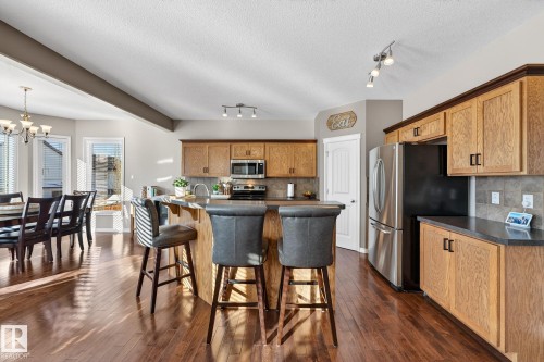 Kitchen with dark countertops, stainless steel appliances, a kitchen bar, dark wood-style flooring, and a textured ceiling - 1734 63A Street, Edmonton, AB - Indoor