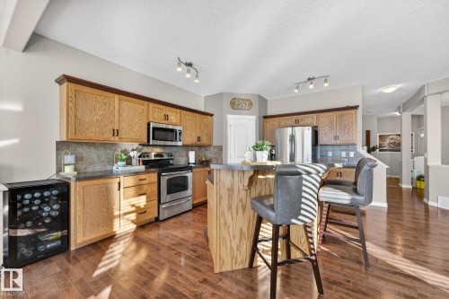 Kitchen featuring beverage cooler, a kitchen bar, stainless steel appliances, tasteful backsplash, and a kitchen island - 1734 63A Street, Edmonton, AB - Indoor Photo Showing Kitchen With Stainless Steel Kitchen