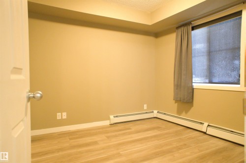 Empty room with light wood finished floors, a baseboard heating unit, and a textured ceiling - 104 5804 Place Nw, Edmonton, AB - Indoor Photo Showing Other Room