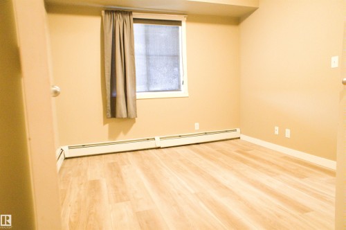 Spare room with light wood-type flooring and baseboard heating - 104 5804 Place Nw, Edmonton, AB - Indoor Photo Showing Other Room