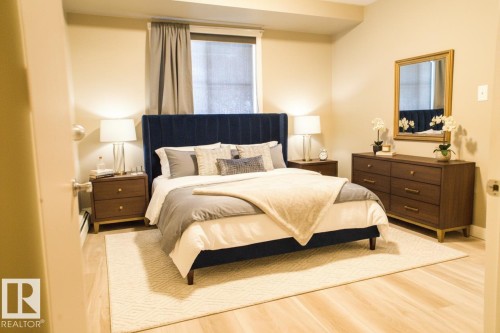 Bedroom featuring wood finished floors and a baseboard radiator - 104 5804 Place Nw, Edmonton, AB - Indoor Photo Showing Bedroom