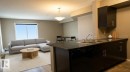 Kitchen with dark countertops, dishwasher, a peninsula, pendant lighting, and open floor plan - 104 5804 Place Nw, Edmonton, AB  - Indoor 