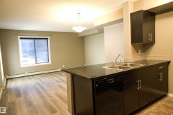 Kitchen featuring dishwasher, decorative light fixtures, a peninsula, a textured ceiling, and baseboard heating - 